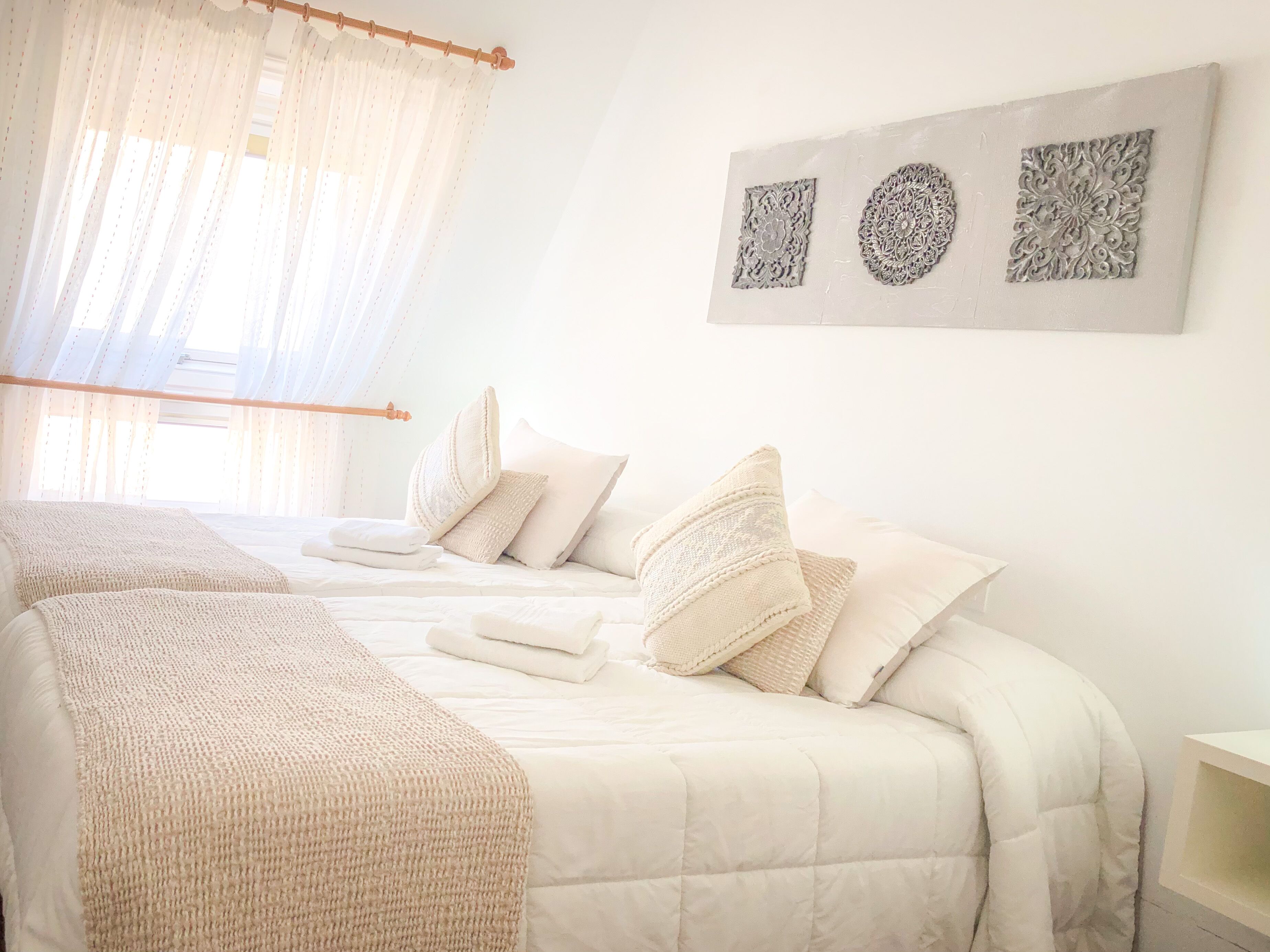 A bedroom with a large bed, two smaller beds, and a bedside table.