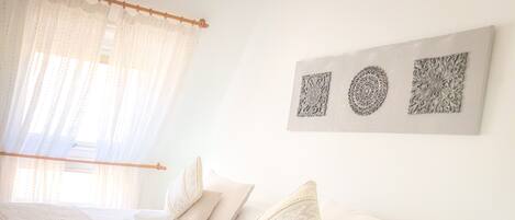 A bedroom with a large bed, two smaller beds, and a bedside table.