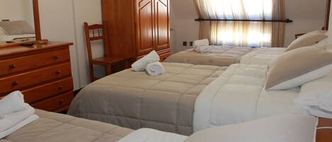 A hotel room with two beds, a wooden dresser, a chair, and a television mounted on the wall.
