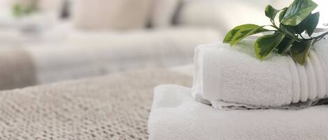Una cama bien tendida con una toalla blanca doblada y una planta verde encima.