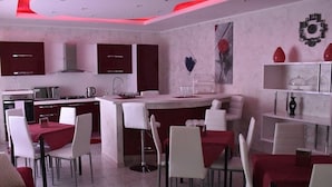 Una cocina moderna con armarios blancos, una isla central y detalles en rojo.