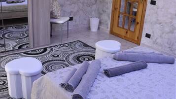 A bedroom with a bed, a wooden door, a TV mounted on the wall, and a patterned rug.