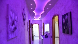 Un pasillo con iluminación morada, una recepción y obras de arte en las paredes.