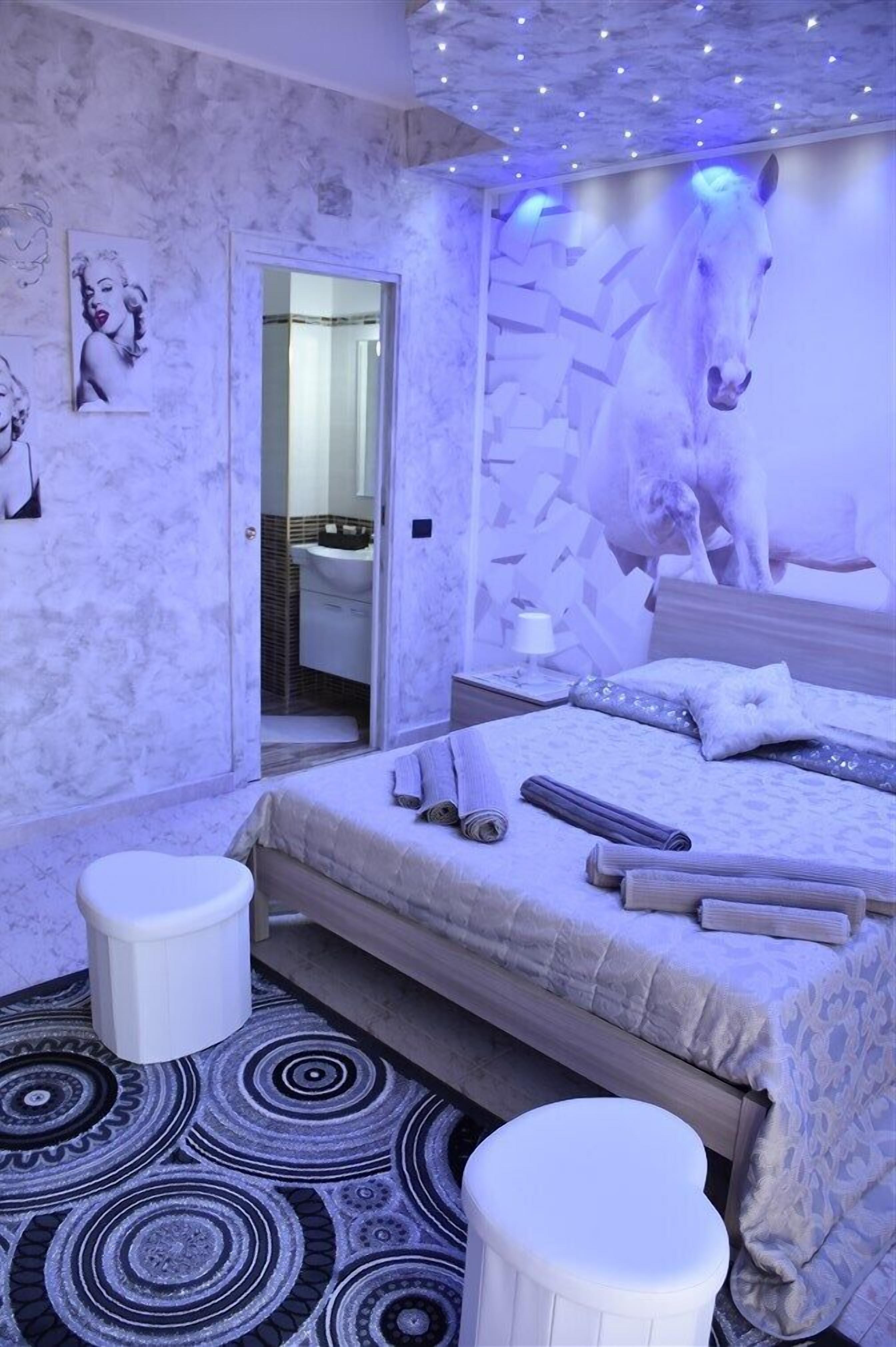 Un dormitorio con una cama, una mesita de noche, un espejo y una escultura de caballo montado en la pared.