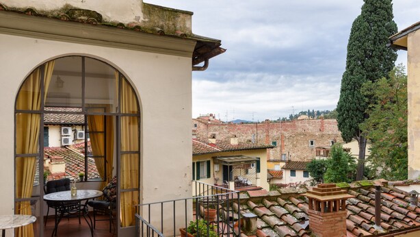 A balcony with a round table and chairs, a potted plant, and a view of the cityscape. - EXCLUSIVE SUITE with Amazing Terrace in the heart of Florence Ponte Vecchio (Firenze)