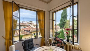 A room with a round table, a chair, a radiator, and a window with curtains. - EXCLUSIVE SUITE with Amazing Terrace in the heart of Florence Ponte Vecchio (Firenze)