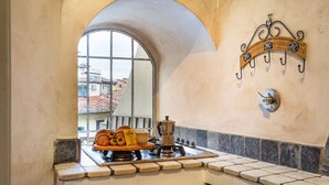 A kitchen with a stove, coffee maker, and a window overlooking a balcony. - EXCLUSIVE SUITE with Amazing Terrace in the heart of Florence Ponte Vecchio (Firenze)