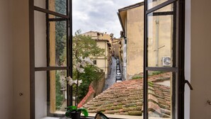 A window view of a narrow street with buildings, a brick staircase, and a potted plant. - EXCLUSIVE SUITE with Amazing Terrace in the heart of Florence Ponte Vecchio (Firenze)