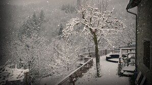 Een besneeuwde buitenruimte met een houten trap die naar een gebouw leidt.