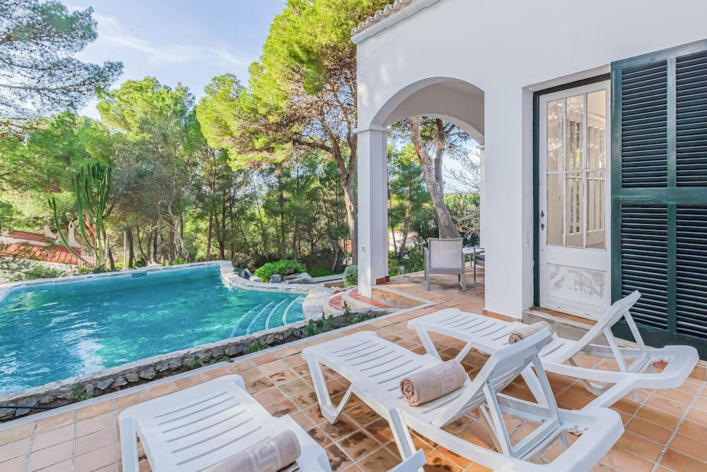 Ein Swimmingpool mit weißen Liegestühlen und einer Pergola.