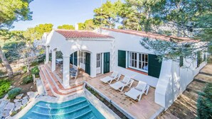 Una villa blanca con piscina, mobiliario exterior y jardín.