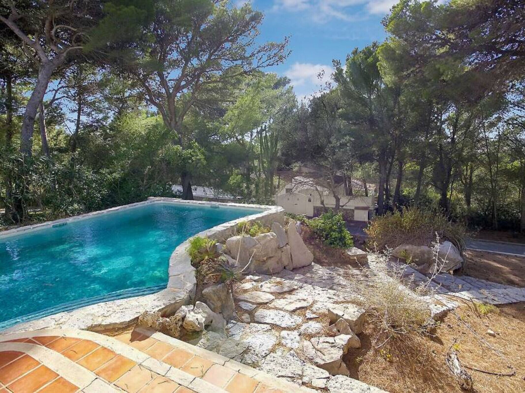 A swimming pool surrounded by natural landscape and stone architecture.