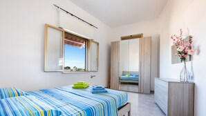 A bedroom with a bed, a dresser, a mirror, and a window with a view.
