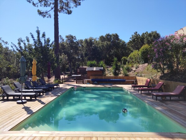 A rectangular pool with a wooden deck, surrounded by lounge chairs and umbrellas. - COMFORTABLE CHALET HEATED POOL BEACHES AND RIVER 10 MIN AWAY (Conca)
