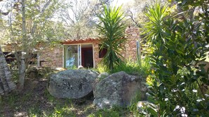 A rustic stone house with a tiled roof, surrounded by large rocks and lush greenery. - COMFORTABLE CHALET HEATED POOL BEACHES AND RIVER 10 MIN AWAY (Conca)