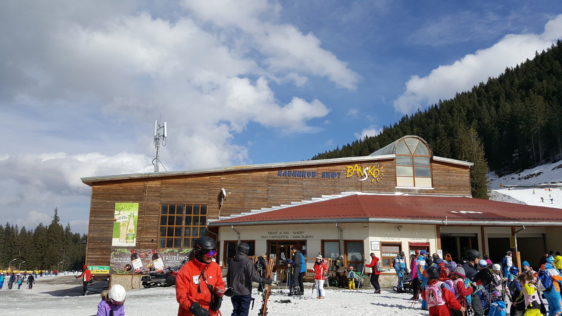 Ein Holzgebäude mit Skiverleih und -service, umgeben von verschneiter Landschaft und Bäumen.