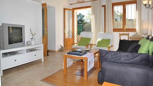 Uma sala de estar com televisão, área de estar e uma mesa de centro de madeira.