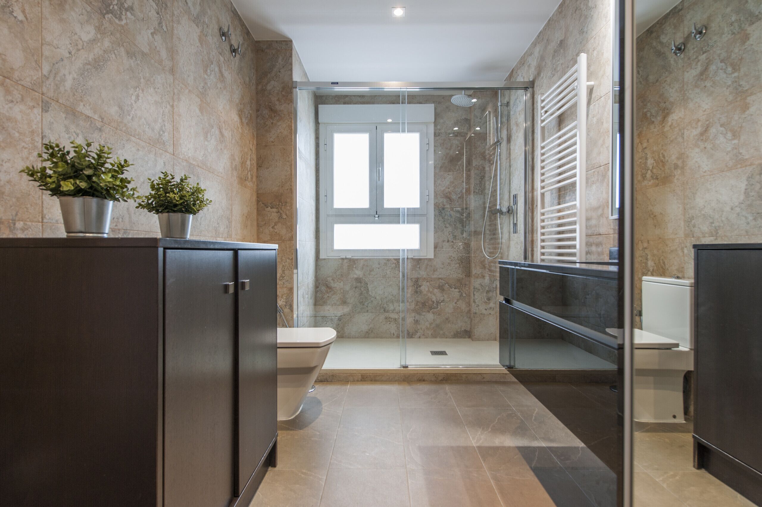 Un baño moderno con ducha envuelta en cristal, inodoro y tocador con gabinete.