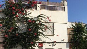 A two-story building with a white facade, a balcony, and a small window.
