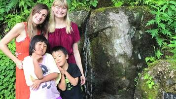 A family of four posing in front of a moss-covered rock with a small waterfall.