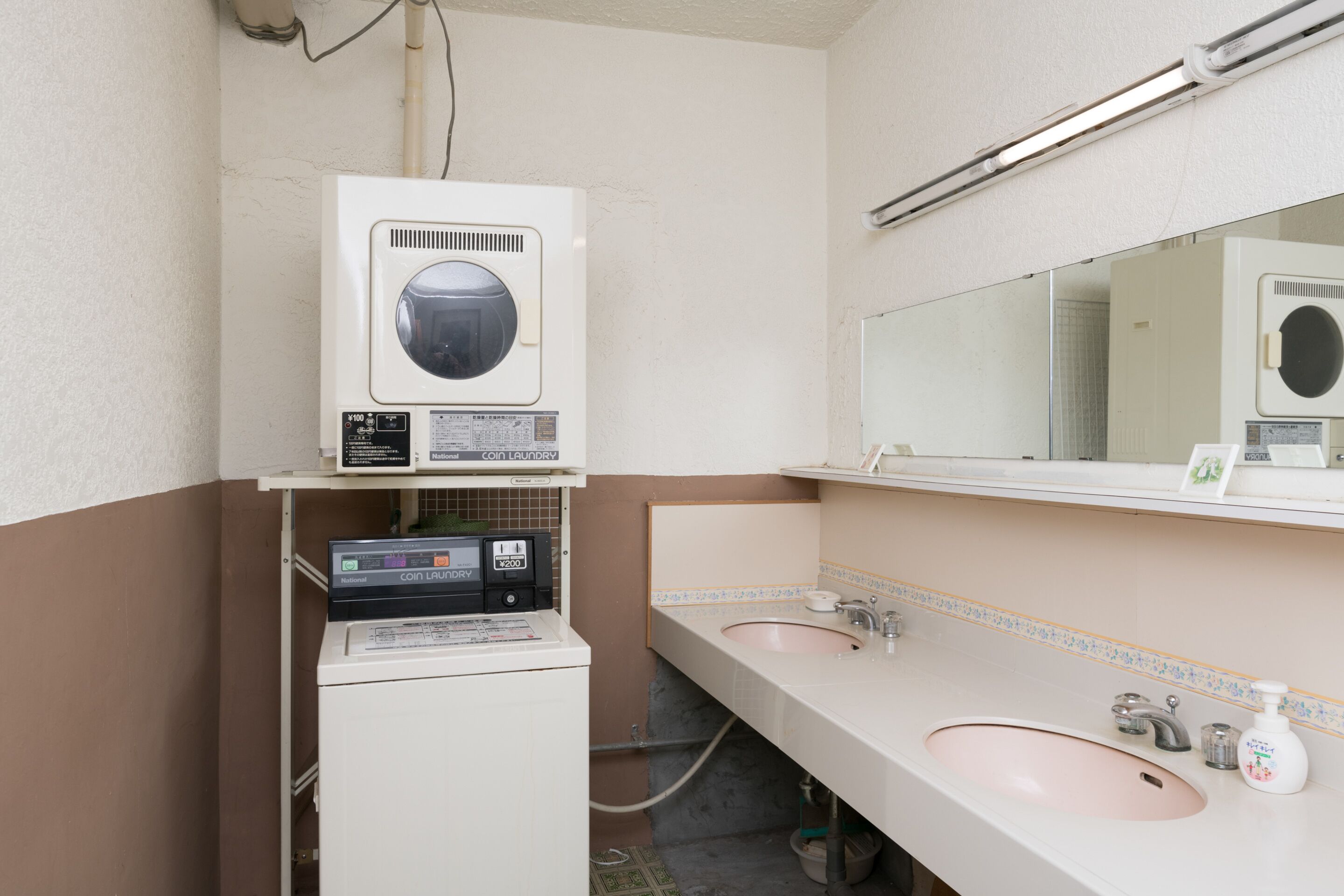 A bathroom with a washing machine, two sinks, and a mirror.