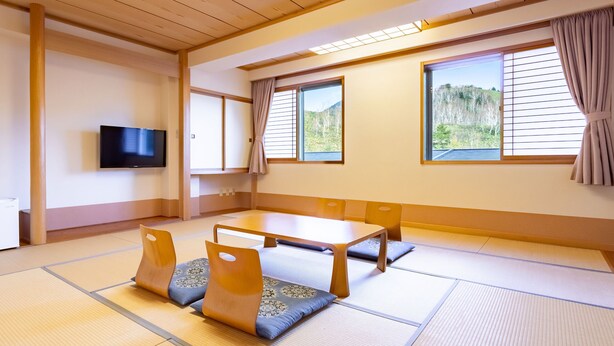A tatami mat room with a low table and cushions, a television, and sliding doors. - Sachinoyu Hotel Shiga Kogen (Yamanouchi)