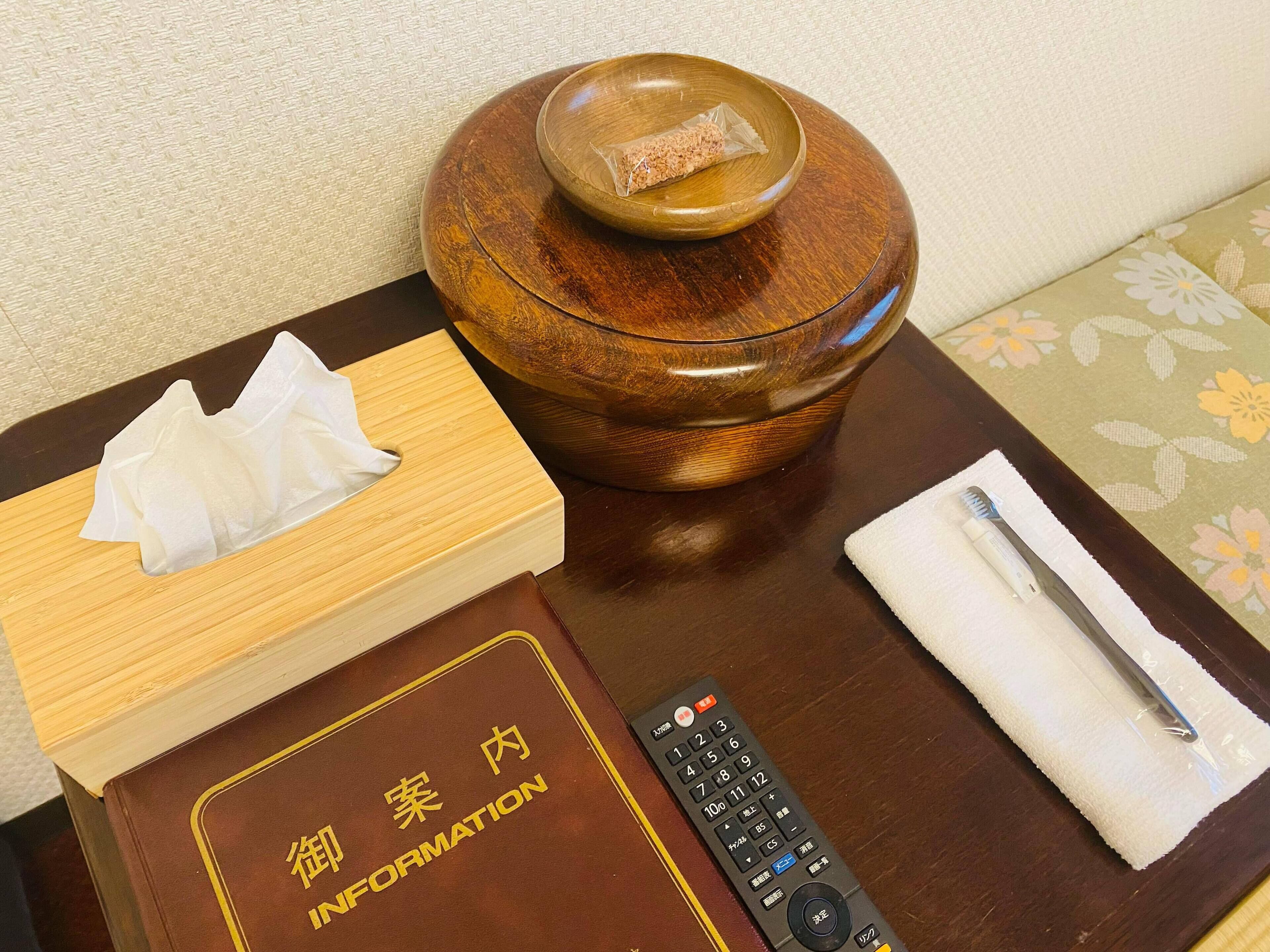 Une table de chevet en bois avec une télécommande, une boîte de mouchoirs et un livre intitulé « Information ».