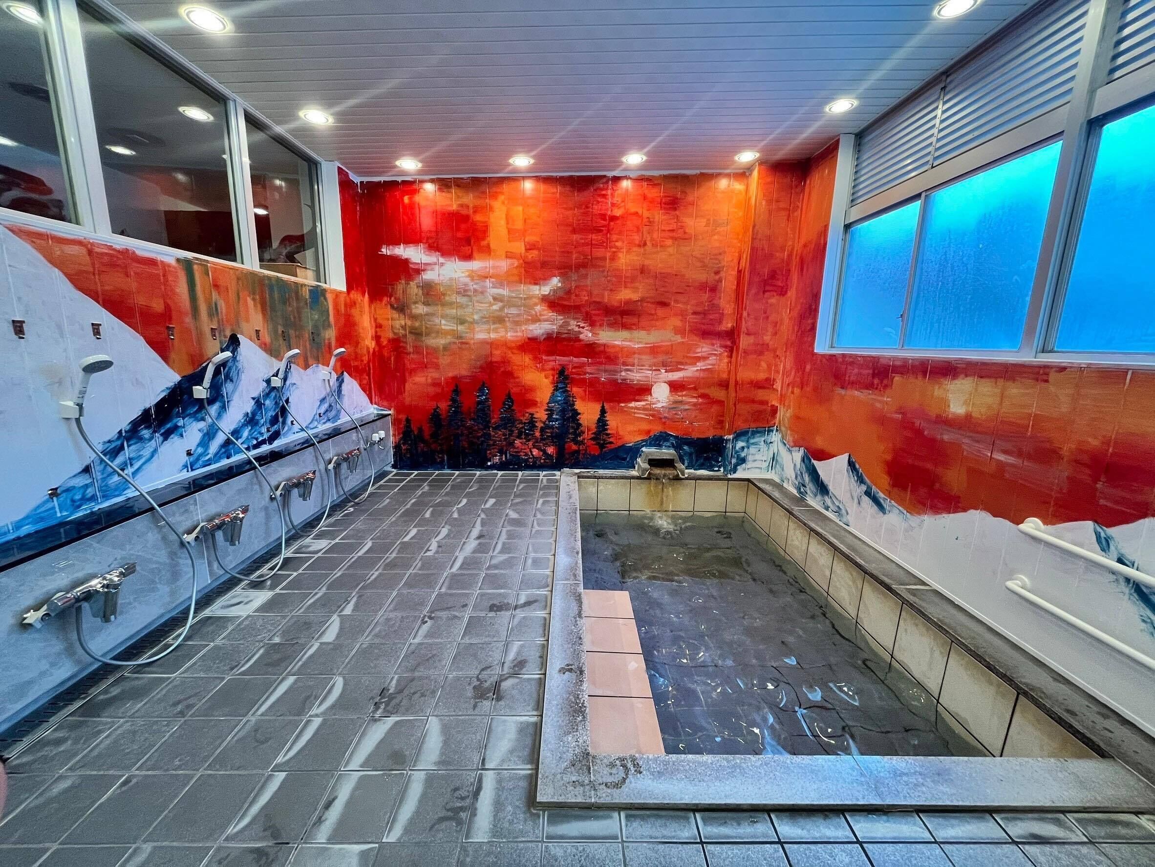 A spa area with a mural of a mountain landscape, a tiled floor, and a window with blue-tinted glass.