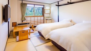 A hotel room with two beds, a wooden desk, a TV, and a window with a view of trees. - Sachinoyu Hotel Shiga Kogen (Yamanouchi)