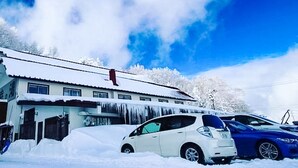 A building with a snow-covered roof and parked cars in front. - Sachinoyu Hotel Shiga Kogen (Yamanouchi)
