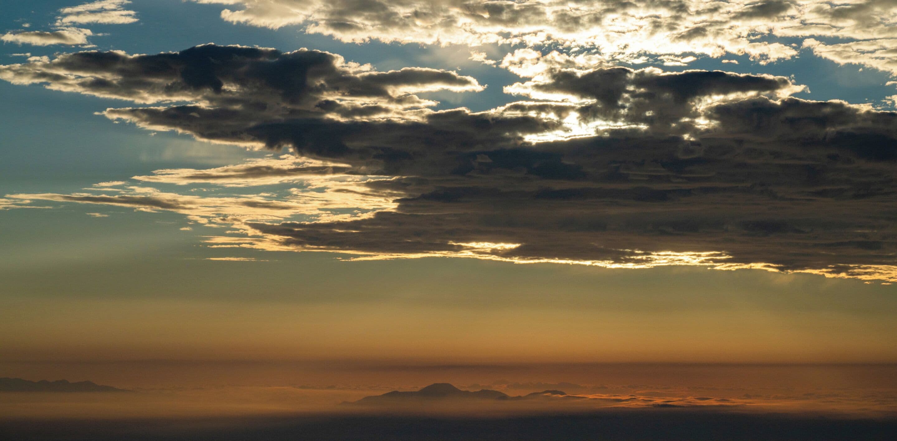 A sunset over a mountainous landscape with clouds.