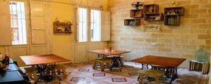 Une pièce avec deux tables en bois, un banc et un mur en briques doté d’étagères.