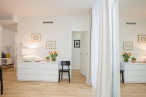 Cozy retreat with a white desk, chair, and potted plant, plus a large window and door to a separate room.