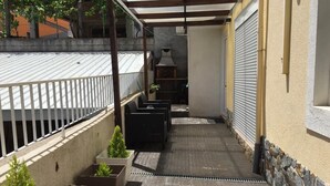A narrow outdoor corridor with planters and a grill area.