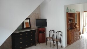 Ein Zimmer mit Fernseher, zwei Stühlen, einem Holzschrank und einem Spiegel an der Wand.