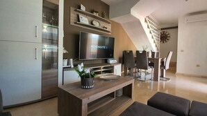 A modern living room with a flat-screen TV, wooden furniture, and a staircase leading to another level. - EL Valle Dúplex, Puerto Rico (puerto rico)