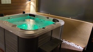 A hot tub with a built-in heater and LED lights, surrounded by wooden paneling and a pebble-lined floor. - EL Valle Dúplex, Puerto Rico (puerto rico)
