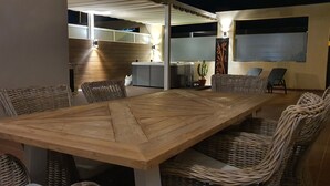 A dining area with a large wooden table and wicker chairs, a small kitchen area with a refrigerator, and a potted plant. - EL Valle Dúplex, Puerto Rico (puerto rico)