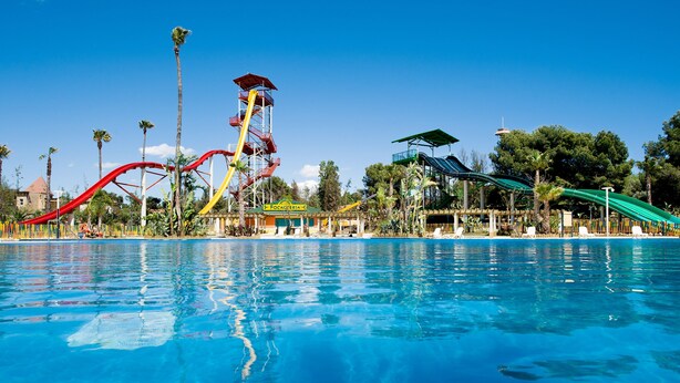 Ein Wasserpark mit Pool, Rutschen und einem hohen Turm.