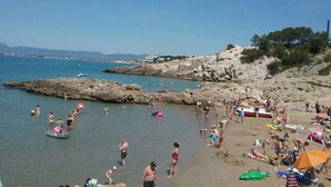 Ein Strand mit felsigem Gelände und klarem, blauem Wasser.