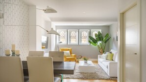 Ein modernes Wohnzimmer mit Essbereich, einem gelben Sessel, einem weißen Sofa und einer großen Pflanze.
