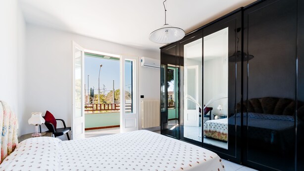 A bedroom with a large bed, a sliding door to a balcony, and a view of the outside. - Entrance, living room, kitchen, 3 spacious rooms, 4p bedroom, 2 bathrooms, garden, place car (Tuglie)