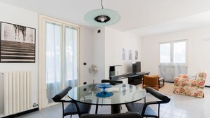 A modern living room with a glass dining table, black chairs, a floral sofa, and a ceiling light fixture. - Entrance, living room, kitchen, 3 spacious rooms, 4p bedroom, 2 bathrooms, garden, place car (Tuglie)