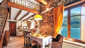 A dining area with a table set for four, a stone wall, and a view of a lake.
