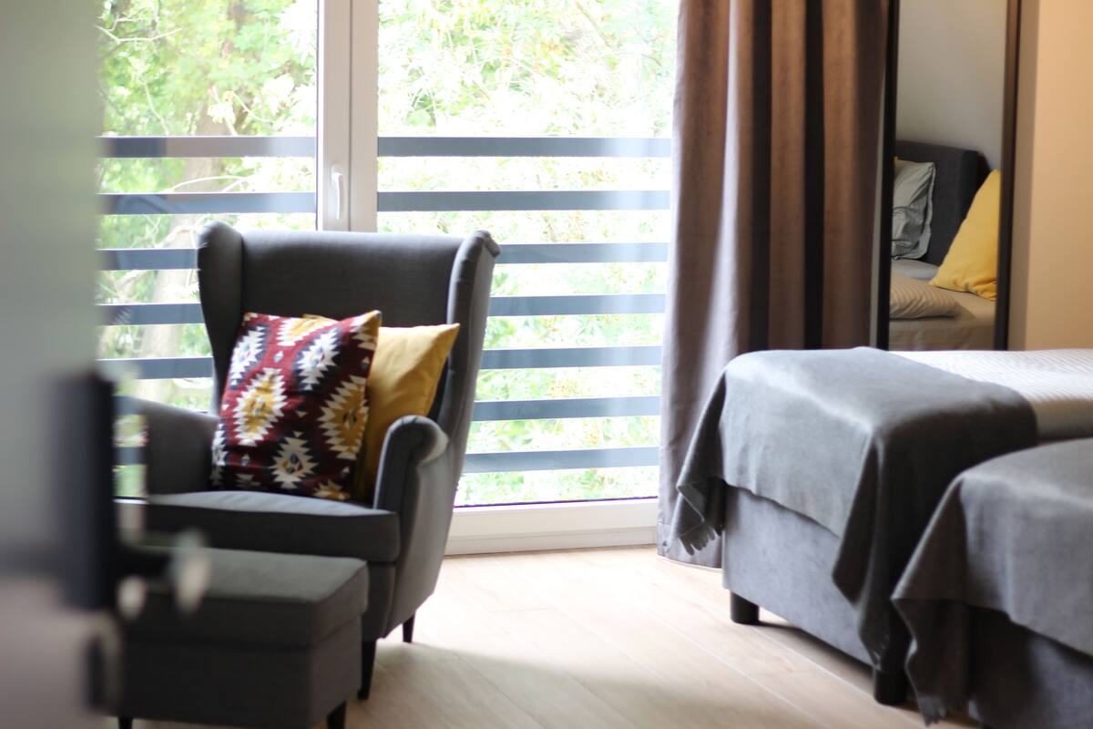 Une pièce avec un lit, une chaise et une fenêtre avec des stores.
