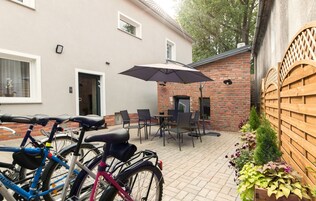 Un patio con dos bicicletas, una mesa, sillas y una sombrilla.