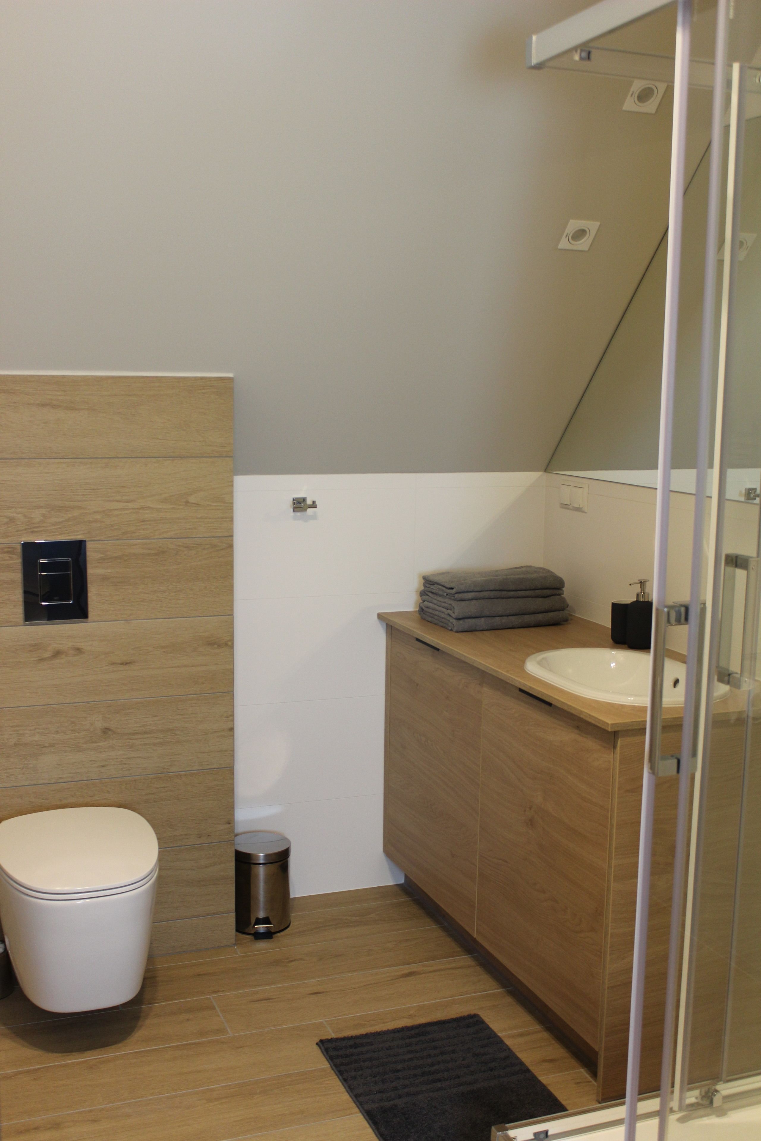 A modern bathroom with a toilet, sink, and a small trash bin.