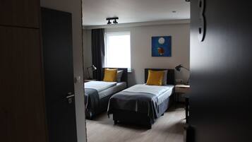 A room with two beds, a desk, a lamp, and a painting on the wall.