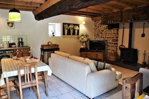 Un salon confortable avec un canapé, une table à manger et des chaises, un téléviseur et une cheminée.