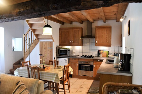Une cuisine chaleureuse avec des meubles en bois, une table à manger et un escalier menant à un autre niveau.